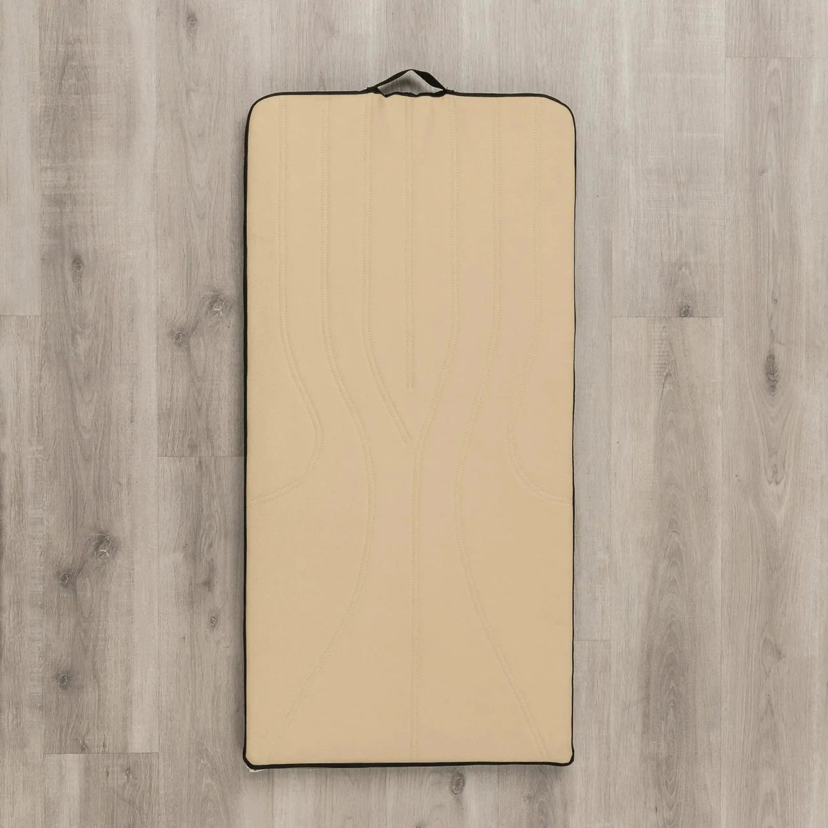 Hegren High Density Pilates-Matte in Beige, Draufsicht auf Holzboden mit Tragegriff am Kopfende