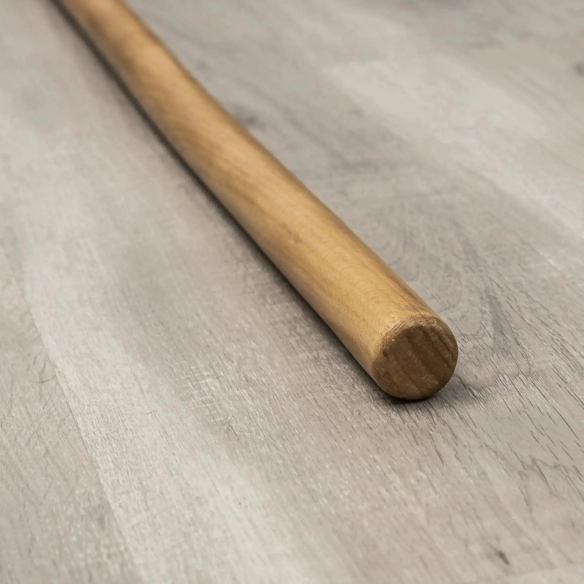Hegren Pilates Wooden Stick 1,10 m aus Eiche, Detail des polierten Stabendes auf Holzboden