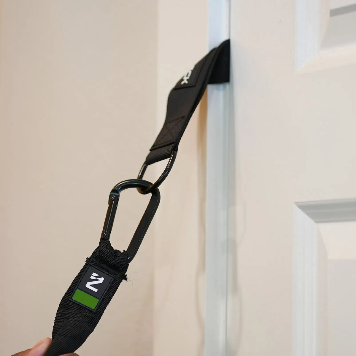 Iron Neck Harness Kit Heavy Zubehör-Set: Detail der Türanker-Schlaufe mit Karabiner an einer weißen Tür