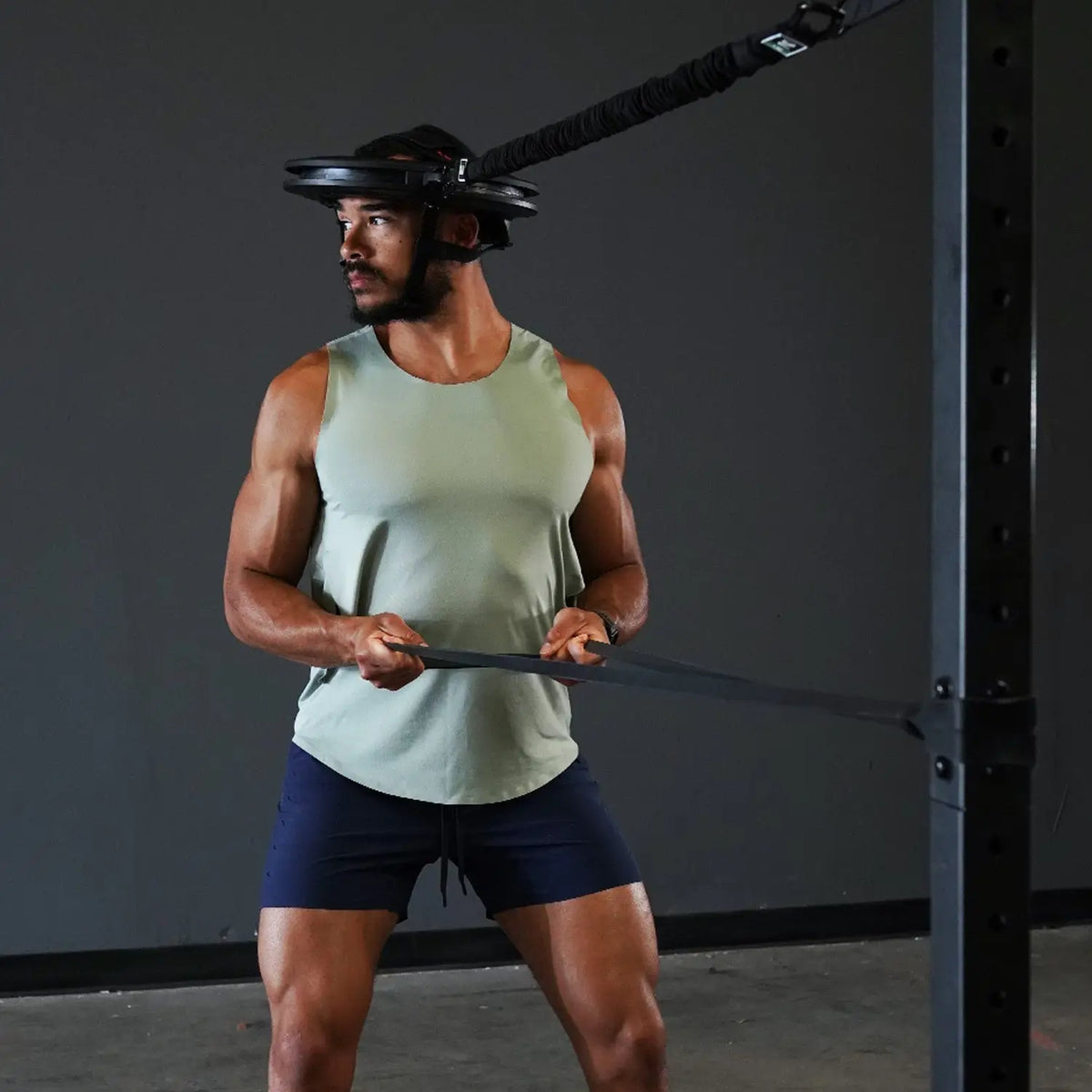 Sportler trainiert mit Iron Neck Strength Kit Band-Set am Rack, Band über den Oberkörper gezogen