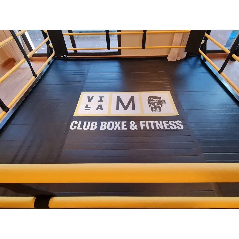 SportCom Boxring-Individualisierung: Detail des schwarzen Bodens mit Club-Logo und gelben Seilen