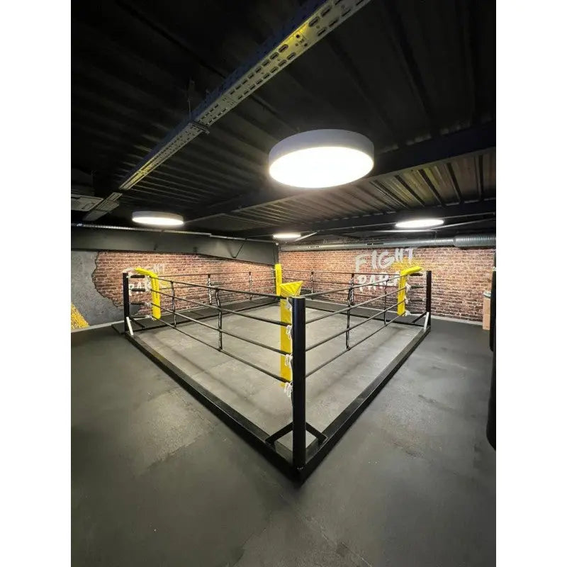 SportCom Freistehender Boxring mit gelben Eckpolstern in einem Studio mit Backsteinwand und grauem Boden
