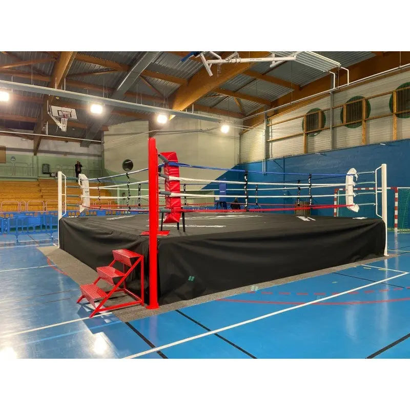 SportCom Pro-Wettkampf-Boxring mit 1 m Podium, mit roter Treppe in einer Schulsporthalle
