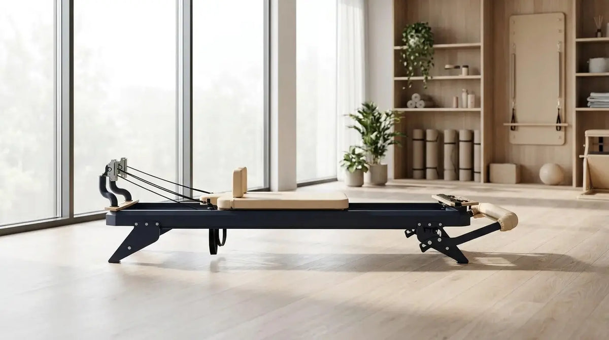 Hegren A Pilates reformer with a steel frame on a light-colored wooden gym floor in a modern studio