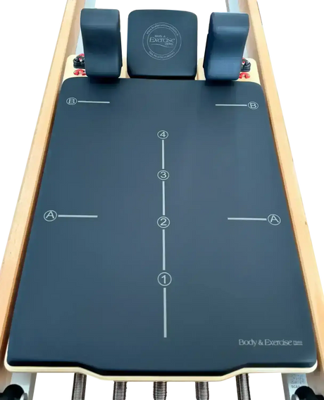 Body & Exercise Reformer Studio P001 aus Buchenholz, Detail der blauen Matte mit Markierungen und Kopfstütze
