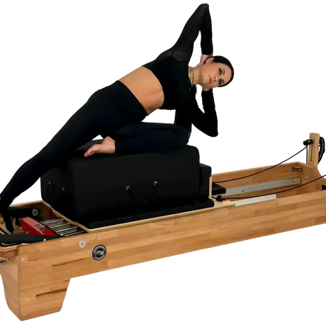 Body & Exercise Reformer Studio P001 aus Buchenholz, Frau bei einer Übung auf dem Reformer, schwarzer Hintergrund
