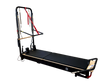Body & Exercise Reformer Tower Black Edition vor schwarzem Hintergrund, Reformer ausgeklappt mit Turm