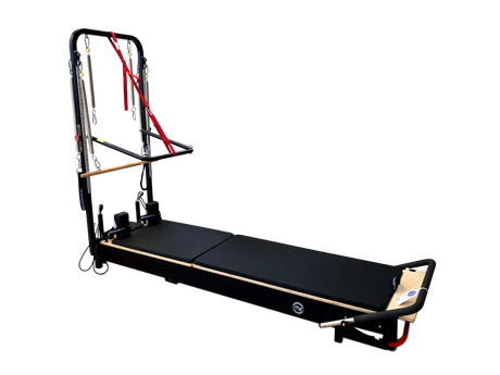 Body & Exercise Reformer Tower Black Edition vor schwarzem Hintergrund, Reformer ausgeklappt mit Turm