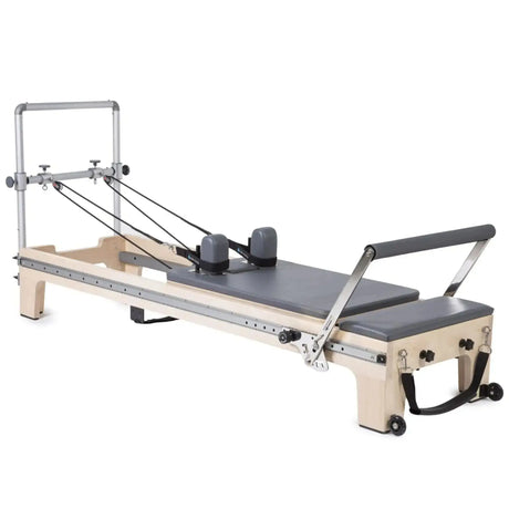 Elina Pilates Master Instructor Reformer aus Ahornholz – Schrägansicht mit Polstern in Grau, freigestellt vor weißem Hintergrund