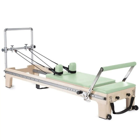 Elina Pilates Master Instructor Reformer aus Ahornholz – Schrägansicht mit Polstern in Grün, freigestellt vor weißem Hintergrund