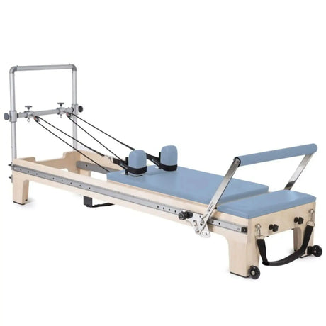 Elina Pilates Master Instructor Reformer aus Ahornholz – Schrägansicht mit Polstern in Ozeanblau, freigestellt vor weißem Hintergrund