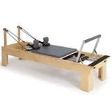Elina Pilates Wooden Reformer aus Rock-Ahorn in Grau, Schrägansicht mit Holzrahmen und Fußstange