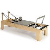 Elina Pilates Wooden Reformer aus Rock-Ahorn in Mokka, Schrägansicht mit Holzrahmen und Fußstange