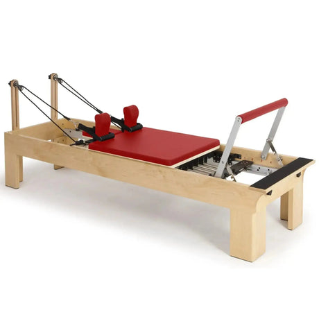 Elina Pilates Wooden Reformer aus Rock-Ahorn in Rot, Schrägansicht mit Holzrahmen und Fußstange