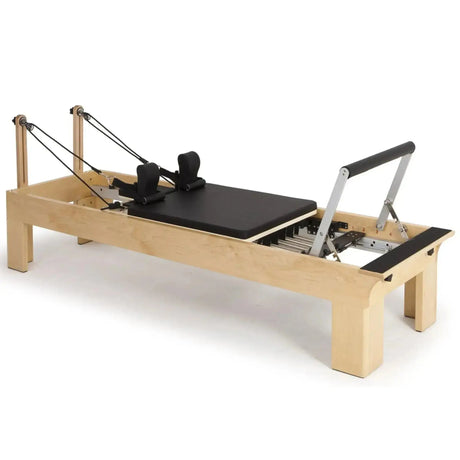 Elina Pilates Wooden Reformer aus Rock-Ahorn in Schwarz, Schrägansicht mit Holzrahmen und Fußstange