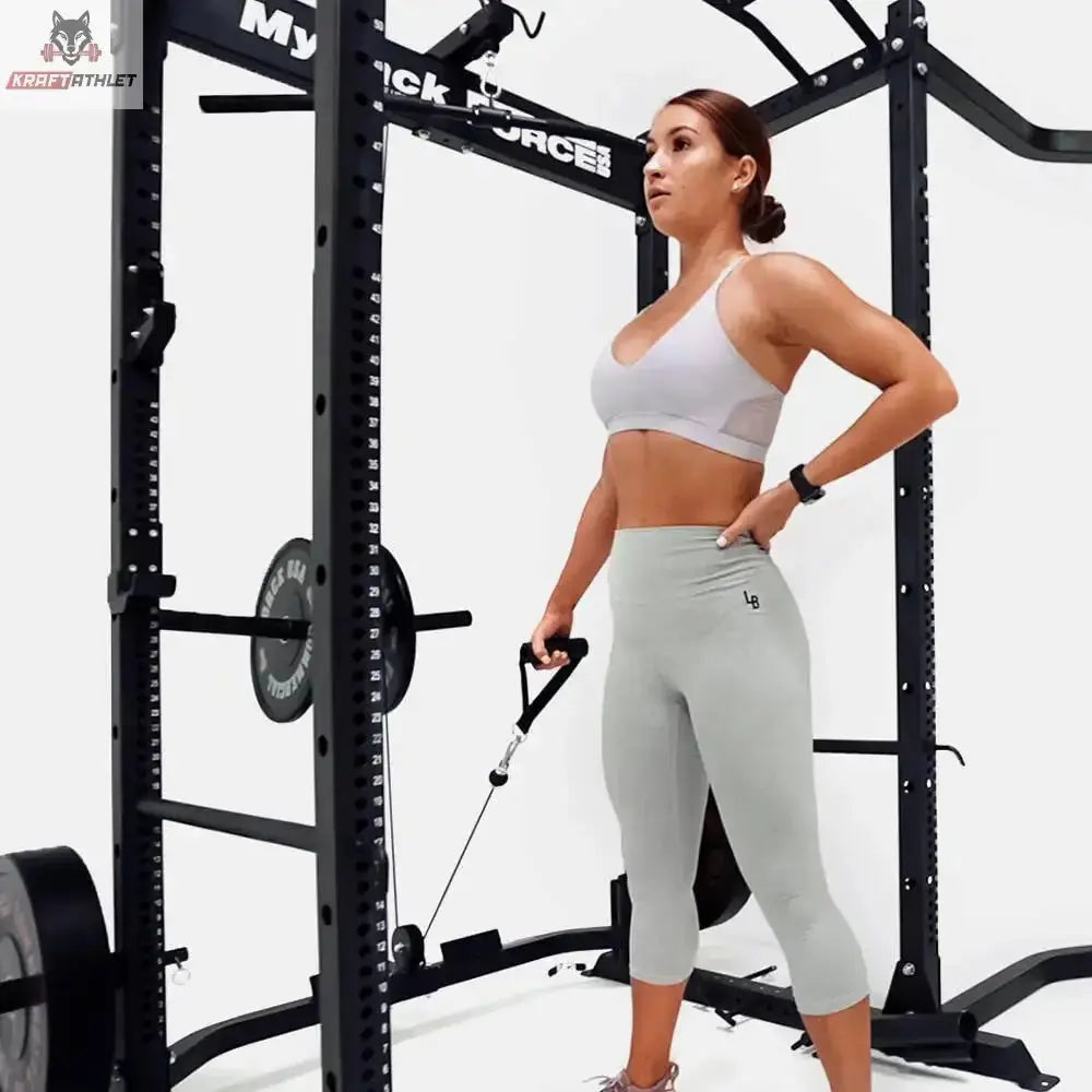 Force USA MyRack Lat Pulldown & Low Row, Frau steht neben dem Rack und hält den Einhandgriff am Seilzug