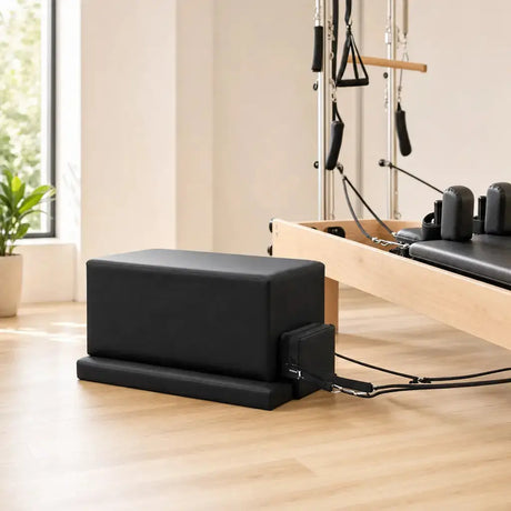 Hegren Pilates Box Modern in Schwarz am Boden vor einem Reformer mit Tower