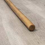 Hegren Pilates Wooden Stick 1,10 m aus Eiche, Detail des polierten Stabendes auf Holzboden