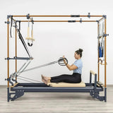 Hegren Pilates Wooden Stick 1,10 m aus Eiche, Frau sitzt auf dem Cadillac-Reformer und zieht den Stab an Seilen