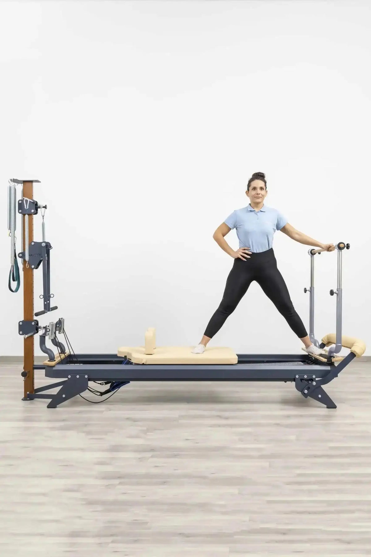 Hegren Stability Bar für den TALMA 62 am Reformer, Frau im Stand mit gespreizten Beinen