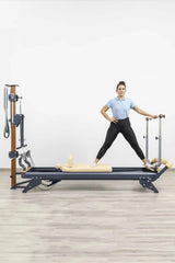 Hegren Stability Bar für den TALMA 62 am Reformer, Frau im Stand mit gespreizten Beinen