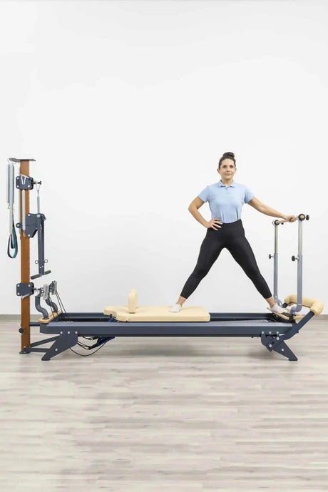 Hegren Stability Bar für den TALMA 62 am Reformer, Frau im Stand mit gespreizten Beinen