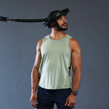 Sportler steht mit Nackentrainer und Band aus dem Iron Neck Strength Kit Band-Set vor grauer Wand