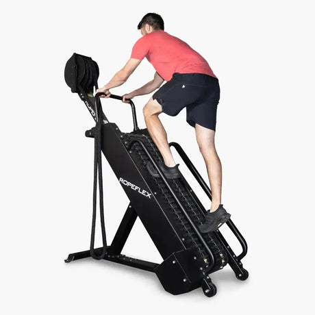 Ropeflex RX4400 Kletter-Seiltrainer, Schrägansicht von vorn mit Mann im roten Shirt am Seil auf Weiß