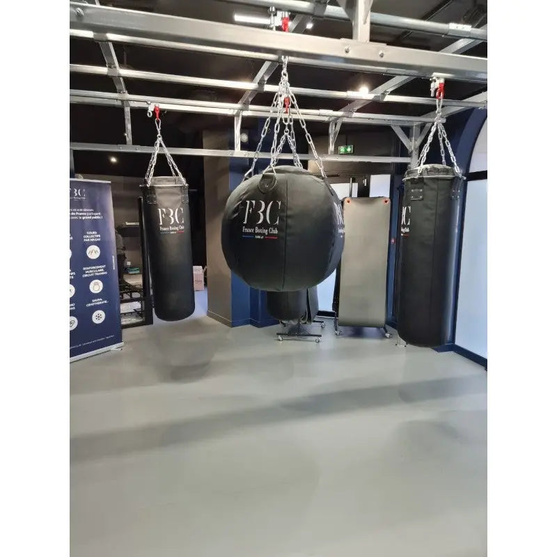 SportCom Birnenförmiger Uppercut-Sandsack Echtleder mit Vereinslogo zwischen Sandsäcken in einer Halle