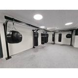 SportCom Birnenförmiger Uppercut-Sandsack Kunstleder, Reihe von Säcken an Gestellen in einem hellen Raum