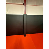 SportCom Flexi-Post Säulenpolster von Dollamur in Schwarz an einer Säule über rotem Mattenboden