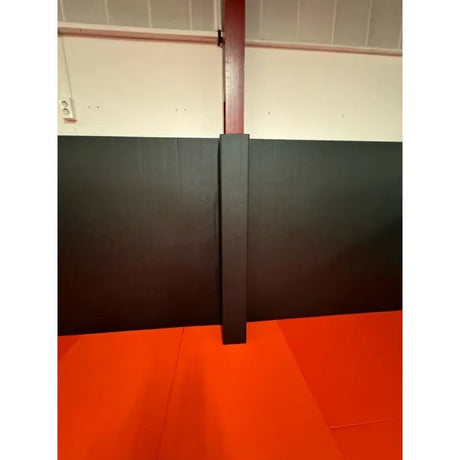 SportCom Flexi-Wall Wandschutz von Dollamur in Schwarz, Detail um eine Säule über orangem Boden