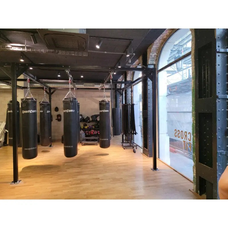 SportCom Förderschiene mit Rahmen für Sandsäcke, in einem Gym mit Rundbogenfenster und Parkett
