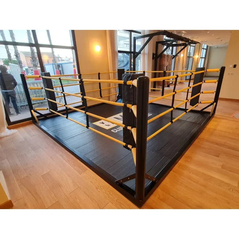SportCom Freistehender Boxring mit gelben Seilen, Seitenansicht mit Tür und Fenstern im Hintergrund