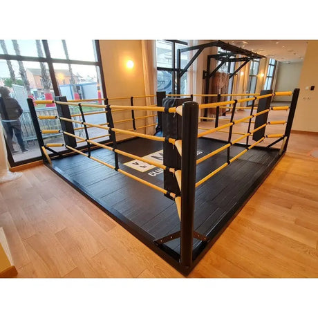 SportCom Freistehender Boxring mit gelben Seilen, Seitenansicht mit Tür und Fenstern im Hintergrund