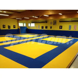 SportCom Judo-Tatami Reisstroh 1 × 1 m, 5 cm, rutschfeste Unterseite, gelbe Felder auf blauer Fläche vor gelben Wänden