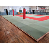 SportCom Judo-Tatami Reisstroh 2 × 1 m, 5 cm, glatte Unterseite, grüne Fläche mit Holzrahmen um rote Säulen, Seitenblick