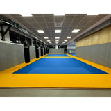 SportCom MMA-Tatami Glattfinish 1 × 1 m, 4 cm, rutschfeste Unterseite, blaue Fläche mit gelbem Rand vor Boxsäcken