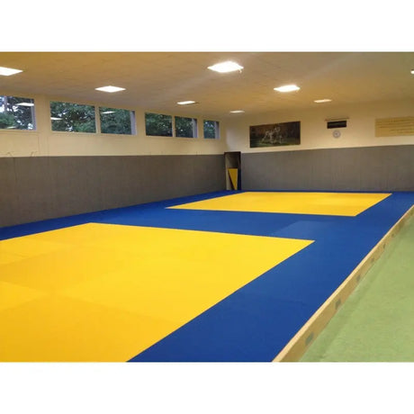 SportCom MMA-Tatami Glattfinish 1 × 1 m, 4 cm, rutschfeste Unterseite, helle Halle mit gelben Feldern auf blauem Grund