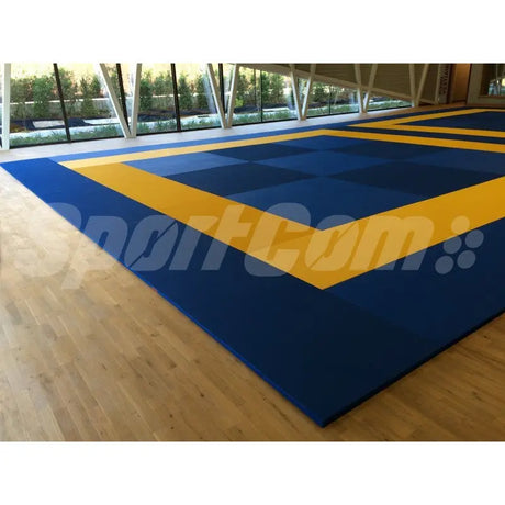 SportCom MMA-Tatami Glattfinish 1 × 1 m, 5 cm, glatte Unterseite, blaue Fläche mit gelbem Rahmen auf Holzboden