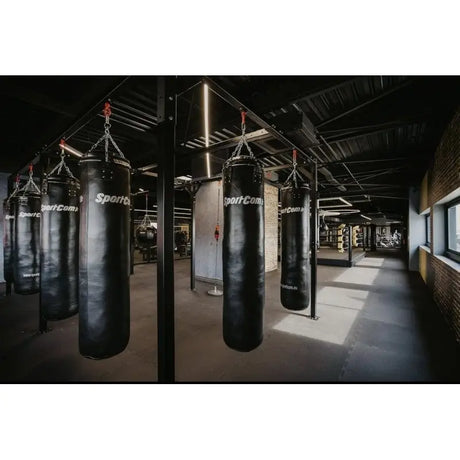 SportCom Modulare Sandsack-Station, in einem dunklen Gym mit Sandsäcken in Reihe