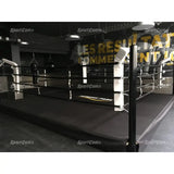 SportCom Pro-Trainingsboxring mit 30 cm Podium, in einer Halle mit Wandschrift, schwarzer Boden
