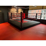 SportCom Pro-Trainingsboxring mit 30 cm Podium, auf rotem Hallenboden, schwarzer Ringboden