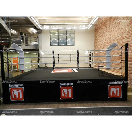 SportCom Pro-Wettkampf-Boxring mit 1 m Podium, in einem Boxclub vor Backsteinwand