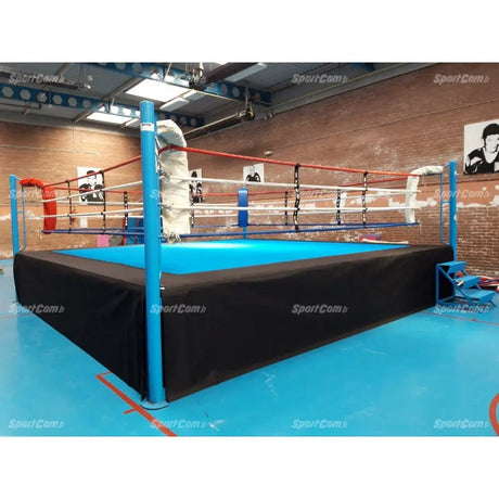 SportCom Pro-Wettkampf-Boxring mit 1 m Podium, mit türkiser Ringfläche vor Backsteinwand