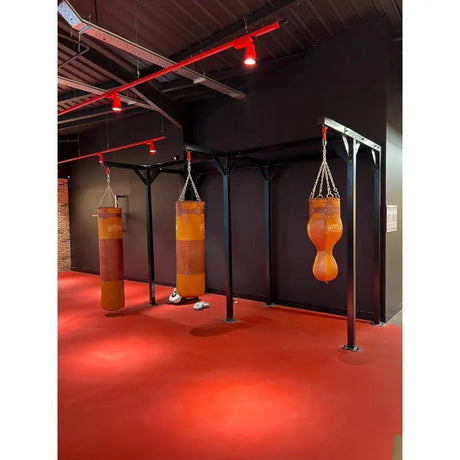SportCom Proboxe Wandstation für Sandsäcke, mit braunen Ledersäcken auf rotem Boden