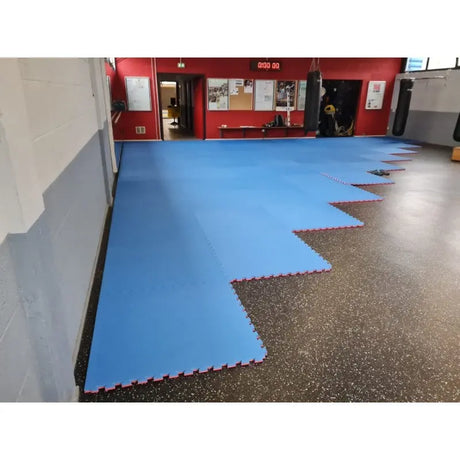 SportCom Puzzlematten 4 cm als blaue Fläche in einem Trainingsraum mit offener Puzzlekante