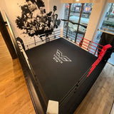 SportCom Ringplane für Podium-Trainingsringe – Schwarze Plane mit weißem Logo im Ring auf Holzboden