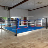 SportCom Trainingsboxring mit 15 cm Podium, in einer Halle mit blauem Boden und Holzparkett