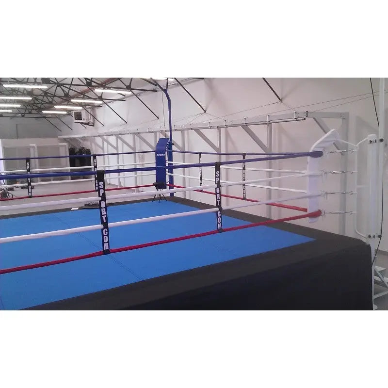 SportCom Wettkampf-Boxringseil mit Hülle, Boxring mit blauer Fläche und weißen Seilen in einer Halle